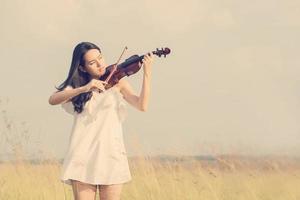bella donna in piedi che suona il violino nel prato foto
