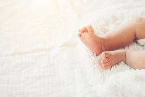 gambe del neonato sul letto bianco.