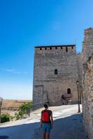 donna che cammina davanti a una torre medievale in pietra foto