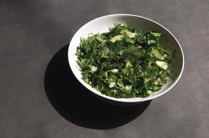 insalata con cetrioli aneto e prezzemolo su un piatto fondo grigio foto