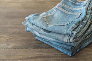 pile di vestiti di jeans su fondo di legno