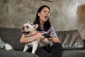 la giovane donna sta giocando alla console per videogiochi con il suo simpatico cane.