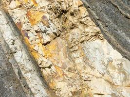 roccia di montagna di pietre di colore grigio, bianco, marrone a strati diagonalmente foto