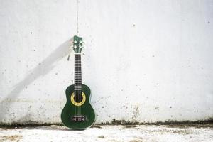 un piccolo ukulele si appoggia a un muro bianco foto