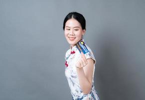 la donna asiatica indossa il vestito tradizionale cinese con la carta che tiene la mano foto