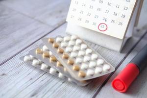 pillole anticoncezionali, calendario e blocco note sul tavolo foto