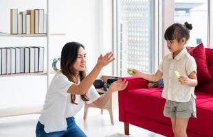 madre asiatica che gioca a fare le bolle con il bambino in soggiorno foto