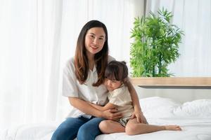 la madre asiatica abbraccia il bambino in camera da letto