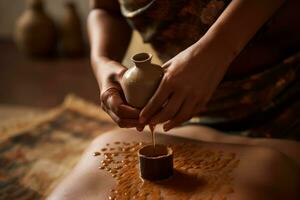 un ayurvedico abhyanga massaggio nel progresso, mostrando mani ritmicamente preparare erbaceo oli per un' caldo pelle. catturare il ringiovanente benessere benefici di ayurvedico massaggio. generativo ai foto