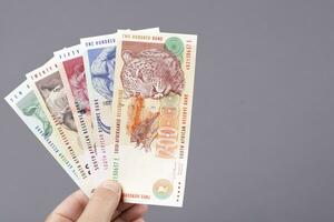 vecchio Sud africano i soldi nel il mano su un' grigio sfondo foto