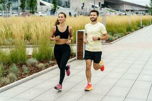 un' in esecuzione istruttore e un' cliente siamo formazione fitness all'aperto. un' donna e un' uomo siamo amici nel fitness Abiti per gli sport. persone uso fitness orologi e in esecuzione scarpe. foto