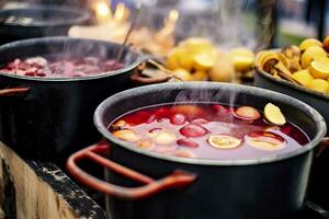 bevande frutta e frutti di bosco caldo vin brulé vino nel pentole con vapore nel strada cibo mercato. generativo ai foto