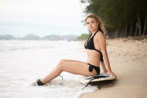 surfer ragazza con sua tavola da surf su il spiaggia. foto