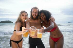 multietnico gruppo di amici avendo divertimento su il spiaggia, potabile birra e avendo divertimento foto