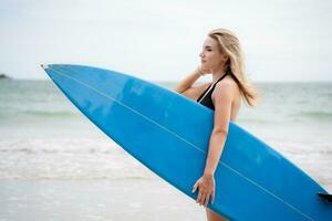 surfer ragazza con sua tavola da surf su il spiaggia. foto