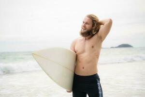 surfer uomo con il suo tavola da surf su il spiaggia. foto