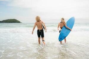 giovane uomo e donna Tenere tavole da surf pronto per camminare in il mare per Surf. foto