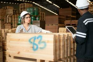 giovane femmina e maschio magazzino lavoratori utilizzando digitale tavoletta per Lavorando nel di legno fabbrica, controllo il pulizia di il tavole foto