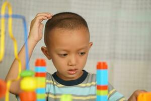 asiatico ragazzo giocando con educativo giocattoli Là siamo molti bellissimo colori su il tavolo nel il Casa. foto