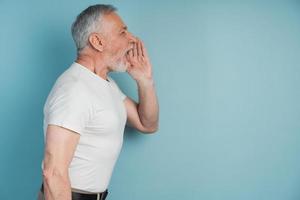 uomo anziano con la barba grigia si erge di profilo su uno sfondo blu foto