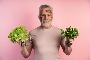 un uomo più anziano, un contadino, tiene in mano della verdura foto