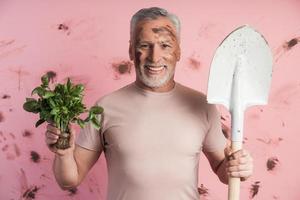 sorridente, attraente, l'uomo più anziano tiene le verdure cresciute foto