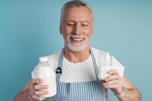 carino nonno con i capelli grigi e la barba tiene una bottiglia di latte foto