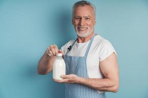 uomo sorridente con in mano una bottiglia di latte foto