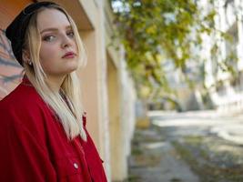 ragazza carina con una giacca rossa con cappello a maglia in piedi vicino a un muro foto