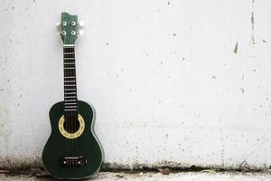 un ukulele verde appoggiato al muro bianco