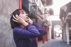 felice giovane donna asiatica che ascolta musica con le cuffie foto