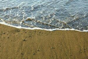 un' spiaggia con onde e sabbia foto