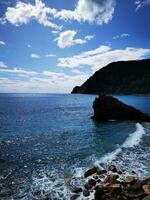 foto di un' sereno paesaggio con un' roccioso litorale e un' maestoso collina nel il distanza