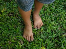 un' poco ragazzo asiatico ragazzo in piedi su il erba a piedi nudi foto