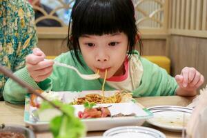 carino poco asiatico bambino ragazza mangiare cibo foto