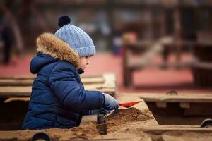 poco ragazzo giocando nel il sandbox foto