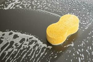 auto pulizia e lavaggio con giallo spugna e schiuma sapone foto