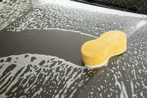 auto pulizia e lavaggio con giallo spugna e schiuma sapone foto