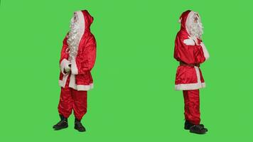 Santa Claus cosplay controlli orologio da polso, guardare a tempo e essere impaziente al di sopra di pieno corpo schermo verde sfondo. padre Natale a piedi in giro su telecamera, di stagione celebrazione. foto