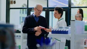 ben informato farmacista nel dispensario offerta più vecchio cliente antibiotici fatto per trattamento malattia sintomi. assistenza sanitaria specialista nel chimico negozio porzione anziano uomo ottenere sbarazzarsi di cuore dolore foto