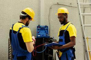 certificato ingegneri chiesto per fare aria condizionatore dai un'occhiata, ricarica refrigerante. lavoro di gruppo colleghi utilizzando collettore calibri per propriamente calibrare il pressione nel HVAC sistema foto