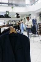 formale maschio blazer sospeso su cremagliera nel moda boutique con sfocato sfondo. maschio giacche ultimo arrivo su grucce e Accessori su mensola nel Dipartimento shopping centro commerciale vicino su selettivo messa a fuoco foto