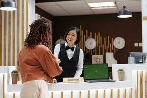 Hotel personale dando accesso chiave carta per ospite, avendo il computer portatile con schermo verde modello su ricezione contatore. dipendente Lavorando a davanti scrivania con croma chiave Schermo e isolato modello. foto