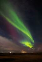 durante orario invernale, famoso settentrionale luci macchiato al di sopra di colline coperto con neve. islandese magico aurora Borealis creare incredibile mostrare quello Brighten su freddo notte cielo con stelle. foto