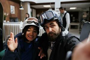 giovane ospiti cattura inverno avventure con selfie su smartphone. miscela di tecnologia e vacanza nel orario invernale per coppia nel neve capi di abbigliamento sciare occhiali e casco a esclusivo montagna ricorrere. foto