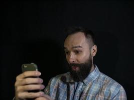 uomo con barba e baffi guarda in un telefono cellulare foto