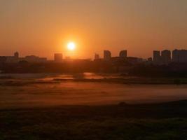 l'alba con la nebbia gialla sul campo, con lo sfondo della città foto