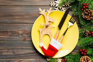 superiore Visualizza di Natale cena su di legno sfondo. piatto, utensile, abete albero e vacanza decorazioni con copia spazio. nuovo anno tempo concetto foto