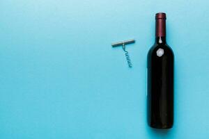 uno bottiglia di rosso vino con cavatappi su colorato tavolo. piatto posizione, superiore Visualizza wth copia spazio foto