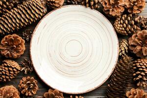 superiore Visualizza di festivo piatto con pino coni su di legno sfondo. nuovo anno cena concetto foto